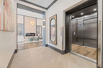 A modern hallway with a wooden floor and a glass elevator at Aster Apartments, Ohio
